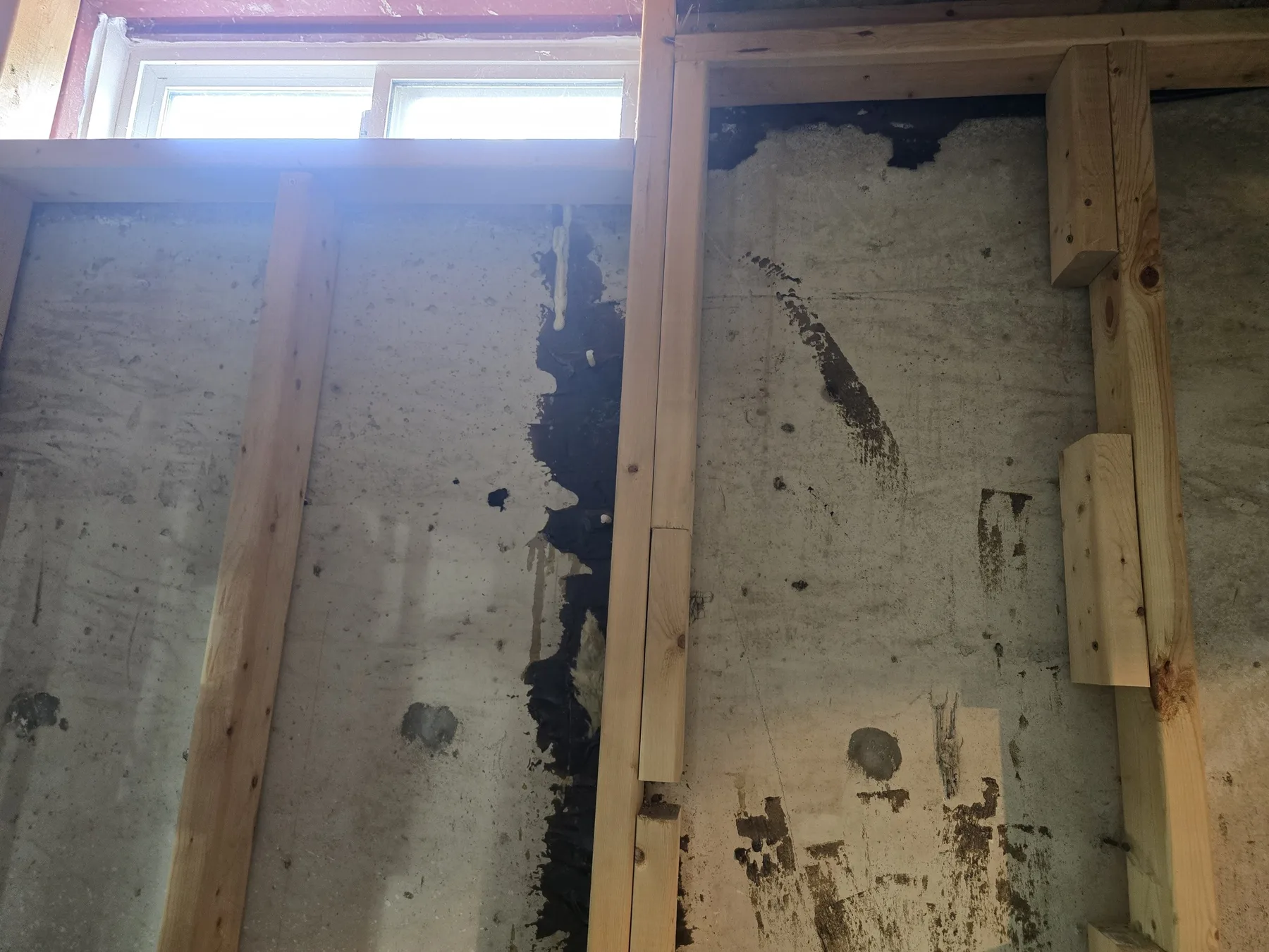 Exposed concrete foundation wall with visible cracking and previous waterproofing work