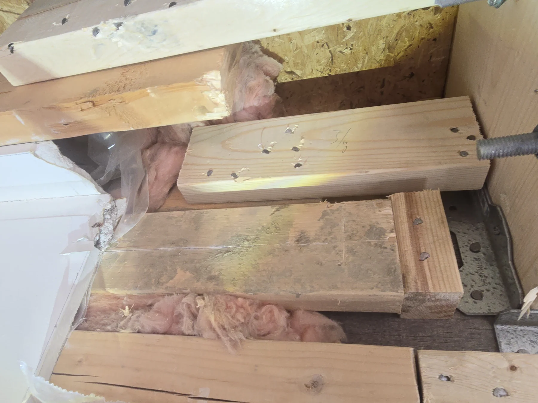 Bolted timber reinforcement and connection hardware documented inside an opened wall