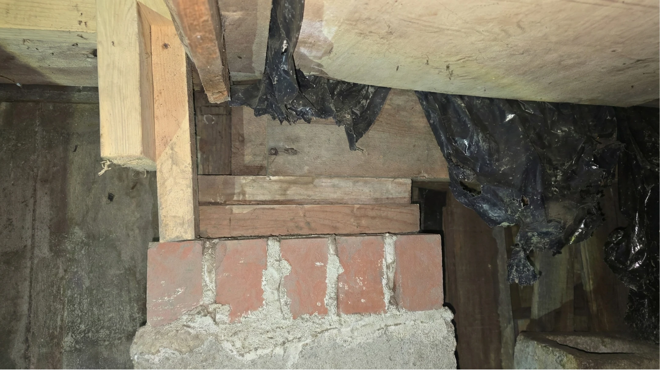 Crawl-space interior showing underfloor framing condition documented in a structural defect report